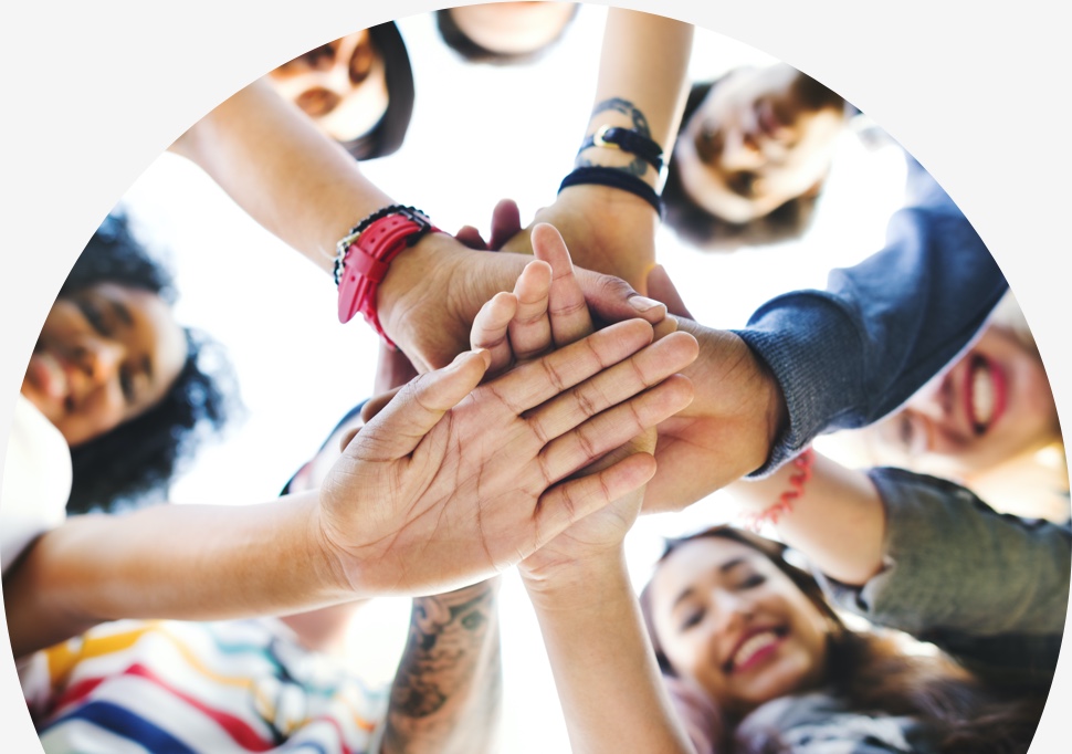 an image of a group of students joining their hands together in collaboration